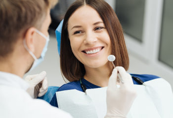 Male Professional Dentist With Gloves And Mask And Discuss What The Treatment Will Look Like Of The Patient's Teeth. Discussion Of The Treatment Plan And Healthy Smile