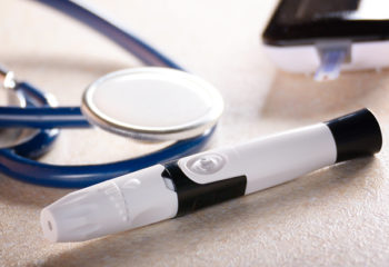 Personal blood glucose meter and lancet with stethoscope on the table