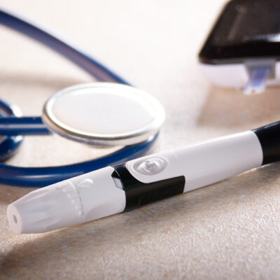 Personal blood glucose meter and lancet with stethoscope on the table