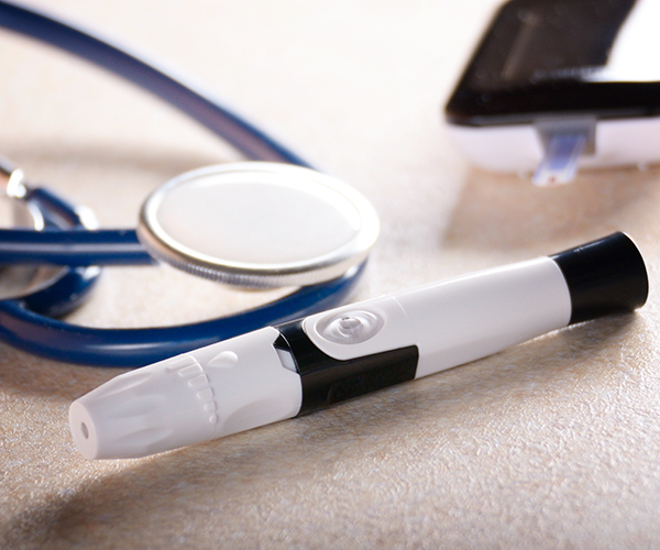 Personal blood glucose meter and lancet with stethoscope on the table