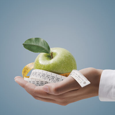 Nutritionist holding a tape measure and an apple, fitness and diet plan concept