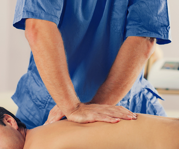 Physiotherapist doing healing treatment on man's back. Therapist wearing blue uniform. Osteopathy. Chiropractic adjustment, patient lying on massage table